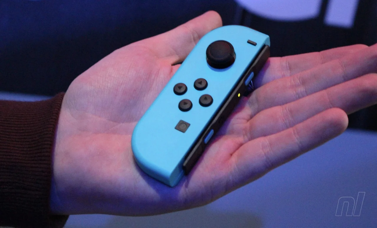 A photograph of a hand holding a blue Nintendo Switch Joy Con